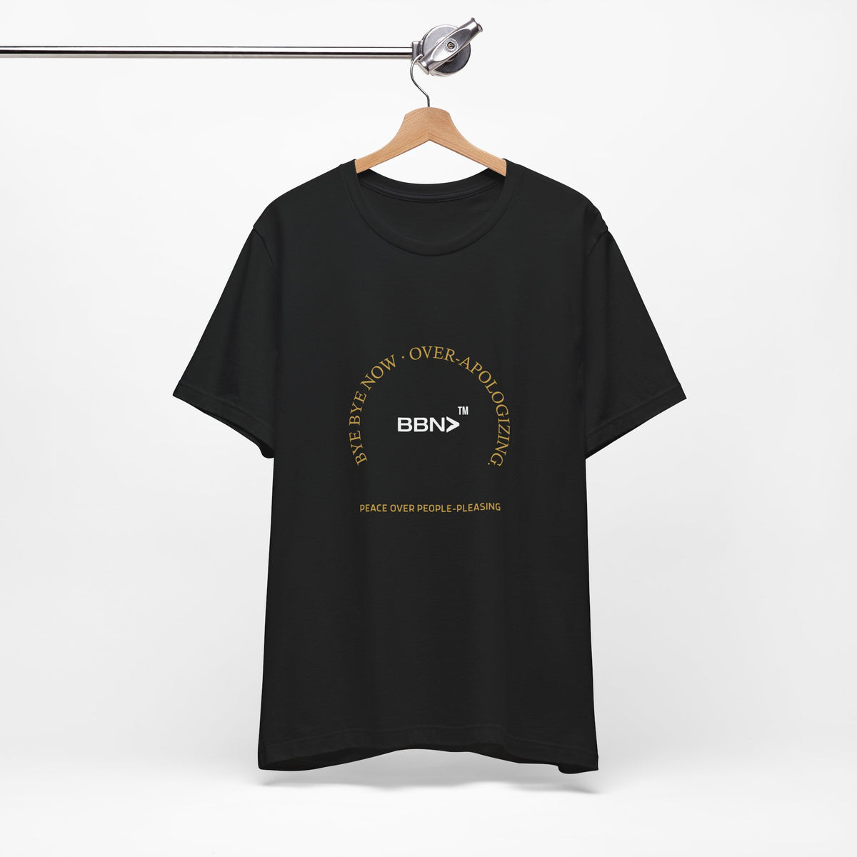 Over-Apologizing Tee in black on a wooden hanger, showing the front print.
