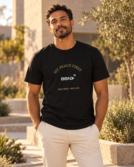 AI styling concept: Man outdoors wearing a black BBN “My Peace First” T-shirt with gold lettering and a white logo.