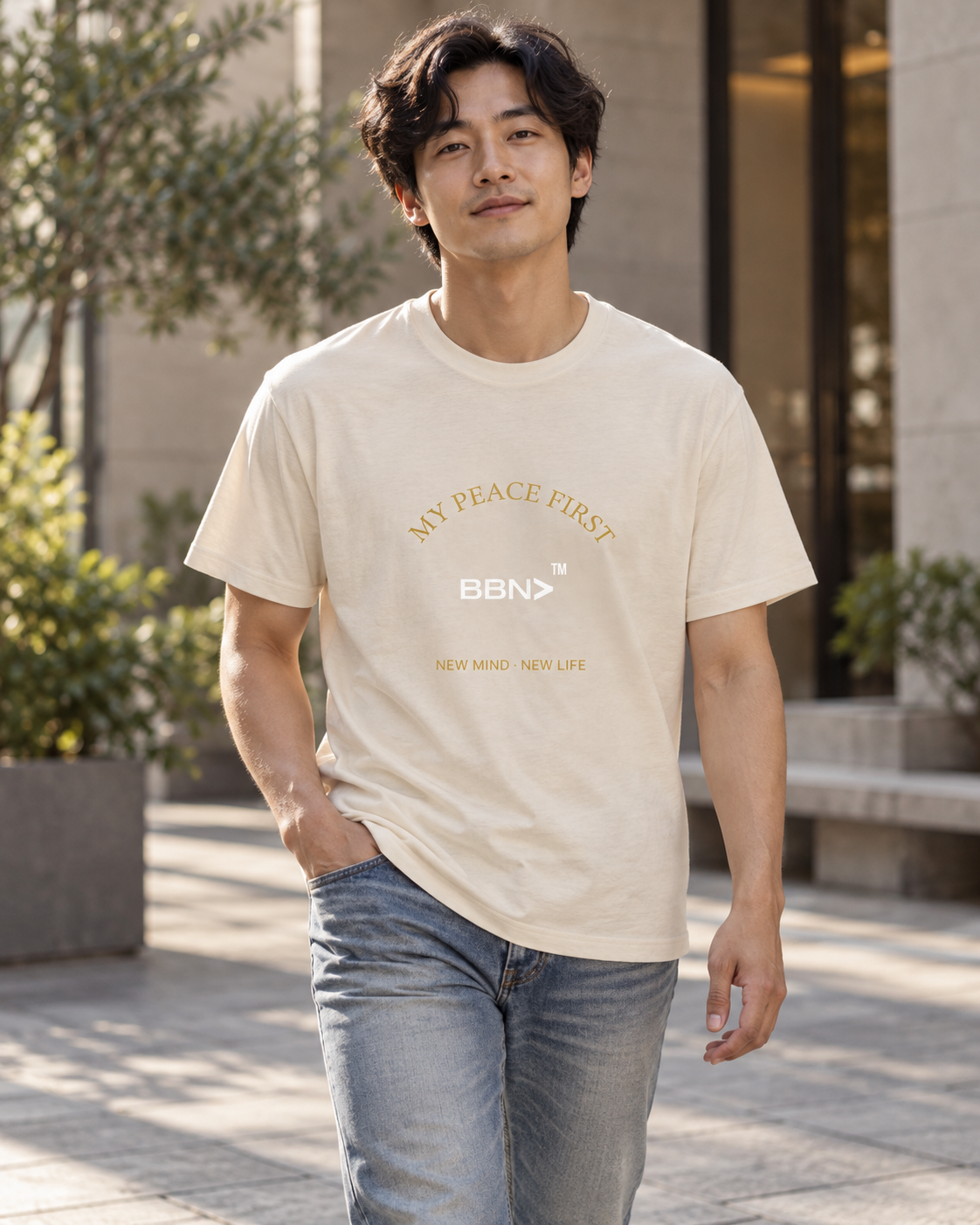 AI styling concept: Man outdoors wearing a natural cream T-shirt with gold “My Peace First” lettering and a white BBN logo.