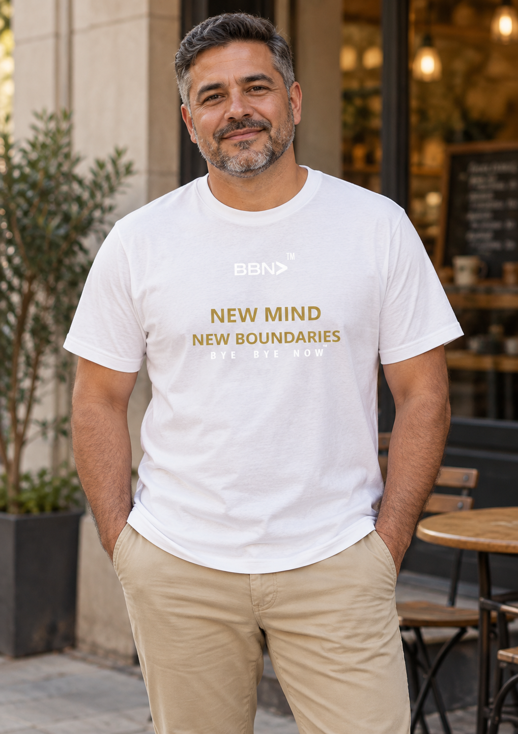 AI styling concept: Man outdoors wearing a white T-shirt with gold “New Mind New Boundaries” lettering and a white BBN logo.