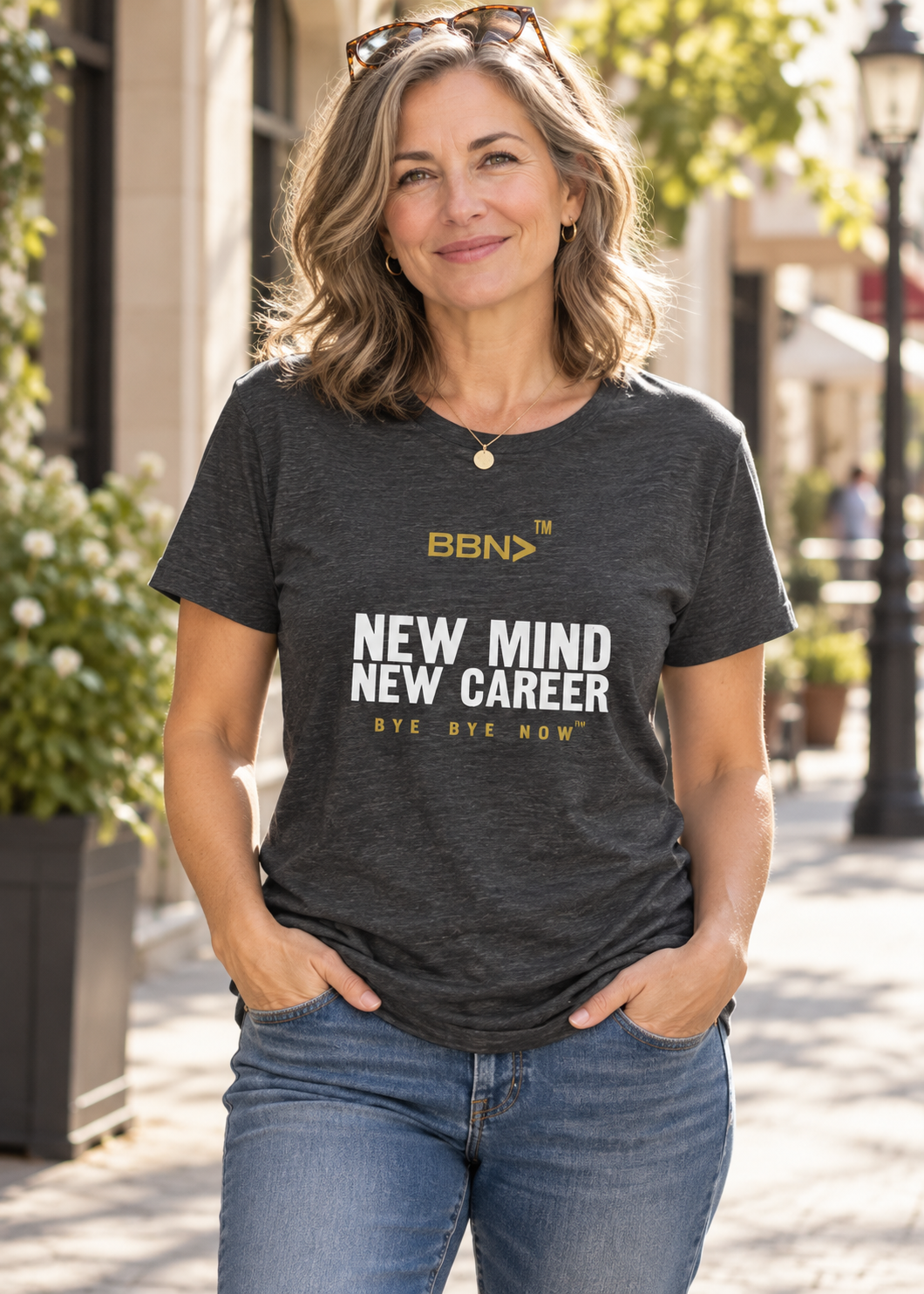 AI styling concept: Woman outdoors wearing a dark gray heather T-shirt with white “New Mind New Career” lettering and a gold BBN logo.
